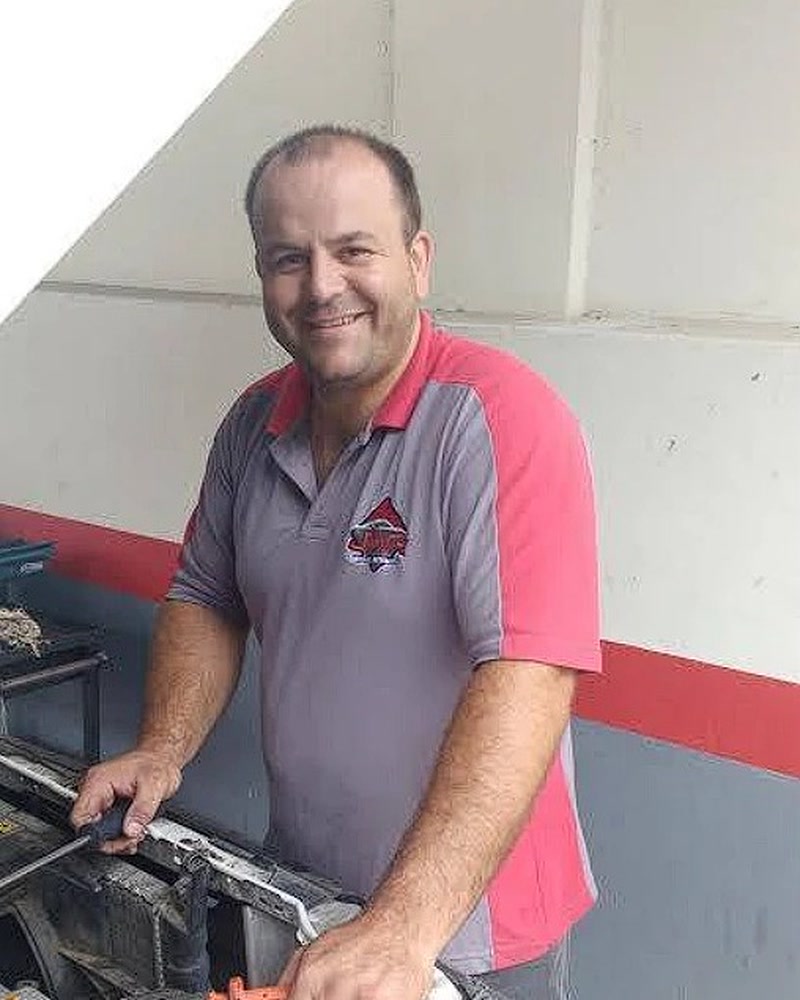 Robi em 2016, sorrindo com a mão no motor de um carro, de camiseta da JWR